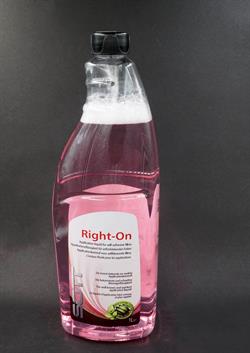 Klar plastflaske med pink væske, sort hætte og dispenser. Label ulæselig.