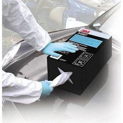 En sort 3M æske med rengøringsklude, en person trækker en klud ud iført beskyttelseshandsker.