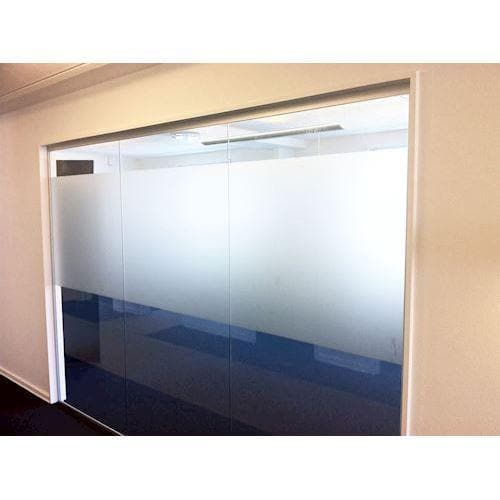 Glasvæg med sandblæst folie, der giver privatliv og lader lys passere, monteret i kontor.