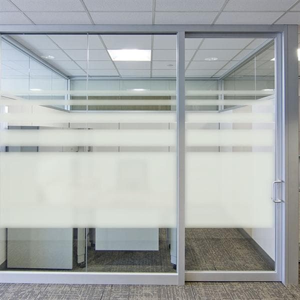 Glasvæg med sandblæst design, vandrette frostede striber og metalramme.