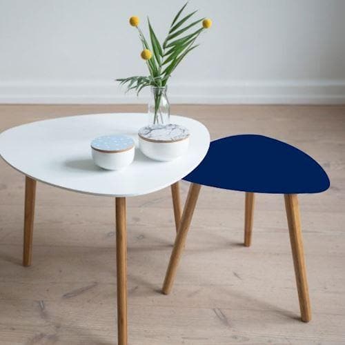 To små borde med træben, hvid og koboltblå top. Vase med gule blomster og to små skåle på det hvide bord.