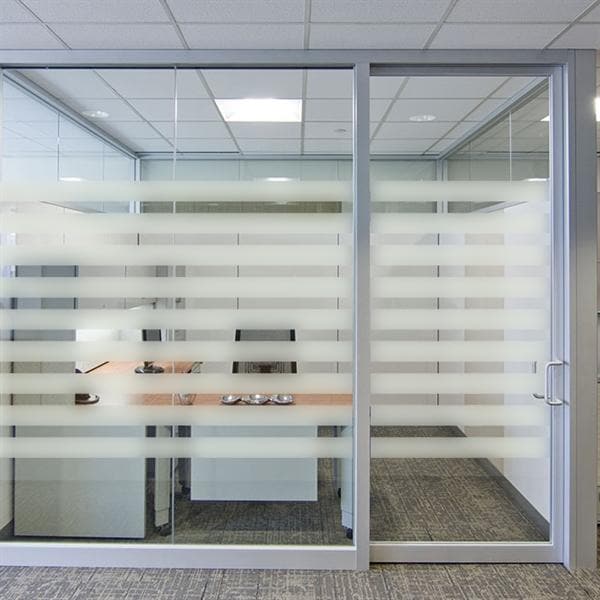 Glasvæg med skiftevis frostede og klare vandrette striber, der giver lys og privatliv på kontoret.